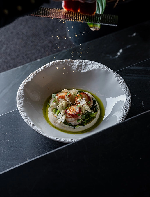A refined scallop dish served with an emulsion and crunchy vegetables at Dans le Noir ? restaurant.