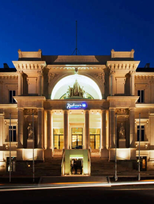Façade illuminée du Radisson Blu Nantes de nuit, mettant en valeur l'architecture classique du bâtiment.