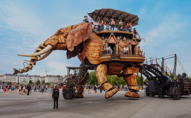 Grand Éléphant des Machines de l’île à Nantes, avec des visiteurs embarqués sur la structure mécanique en bois.