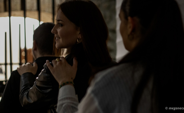 Un groupe de personnes avance en file indienne, une main posée sur l’épaule de la personne devant dans une ambiance tamisée.